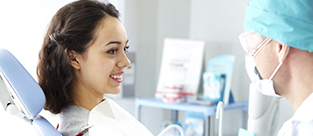 Young female patient looking at dentist while he describing the process of dental treatment